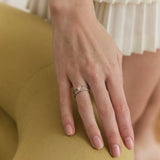 Hand wearing lab-grown diamond engagement ring and wedding band on gold chair