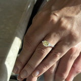 Hand wearing a marquise yellow lab-grown diamond engagement ring with white accent stones