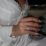 Woman wearing lab-grown diamond rings and bracelet holding cocktail in elegant setting