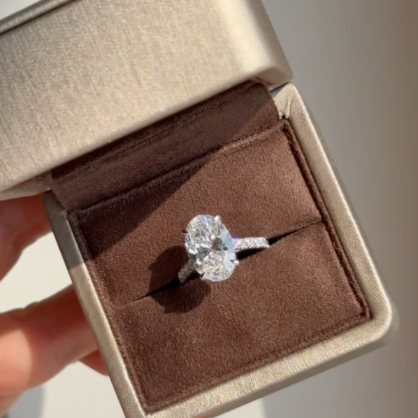 Oval lab-grown diamond engagement ring in a jewelry box, sparkling in natural light