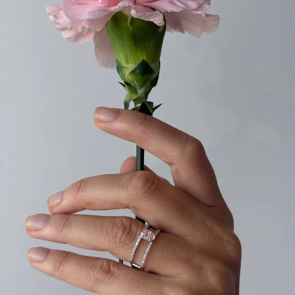 Hand with lab-grown diamond rings holding a pink carnation flower