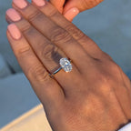 Oval lab-grown diamond engagement ring on woman's hand with manicured nails in natural light