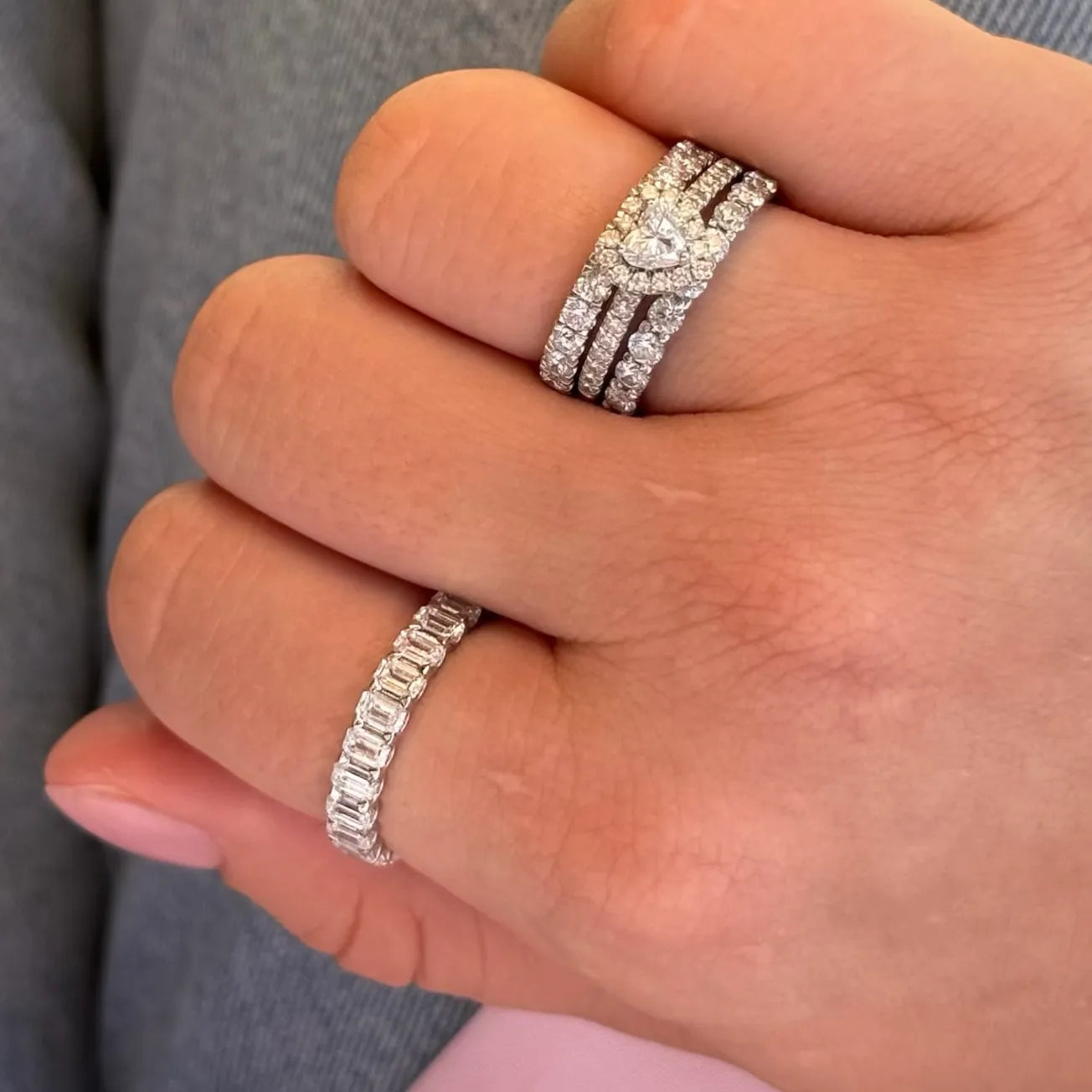 Hand wearing lab-grown diamond eternity rings and heart-shaped diamond ring stack