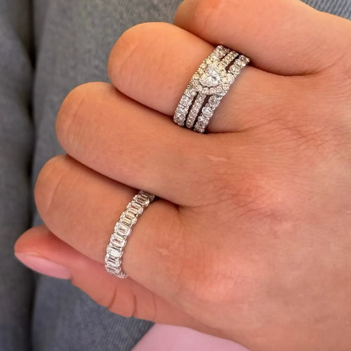 Hand wearing lab-grown diamond eternity rings and heart-shaped diamond ring stack