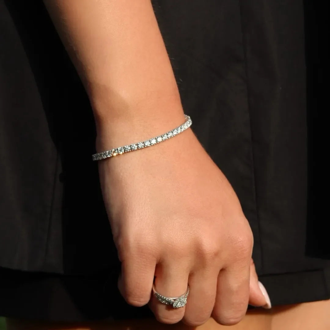 Woman wearing lab-grown diamond tennis bracelet and matching diamond ring against black dress