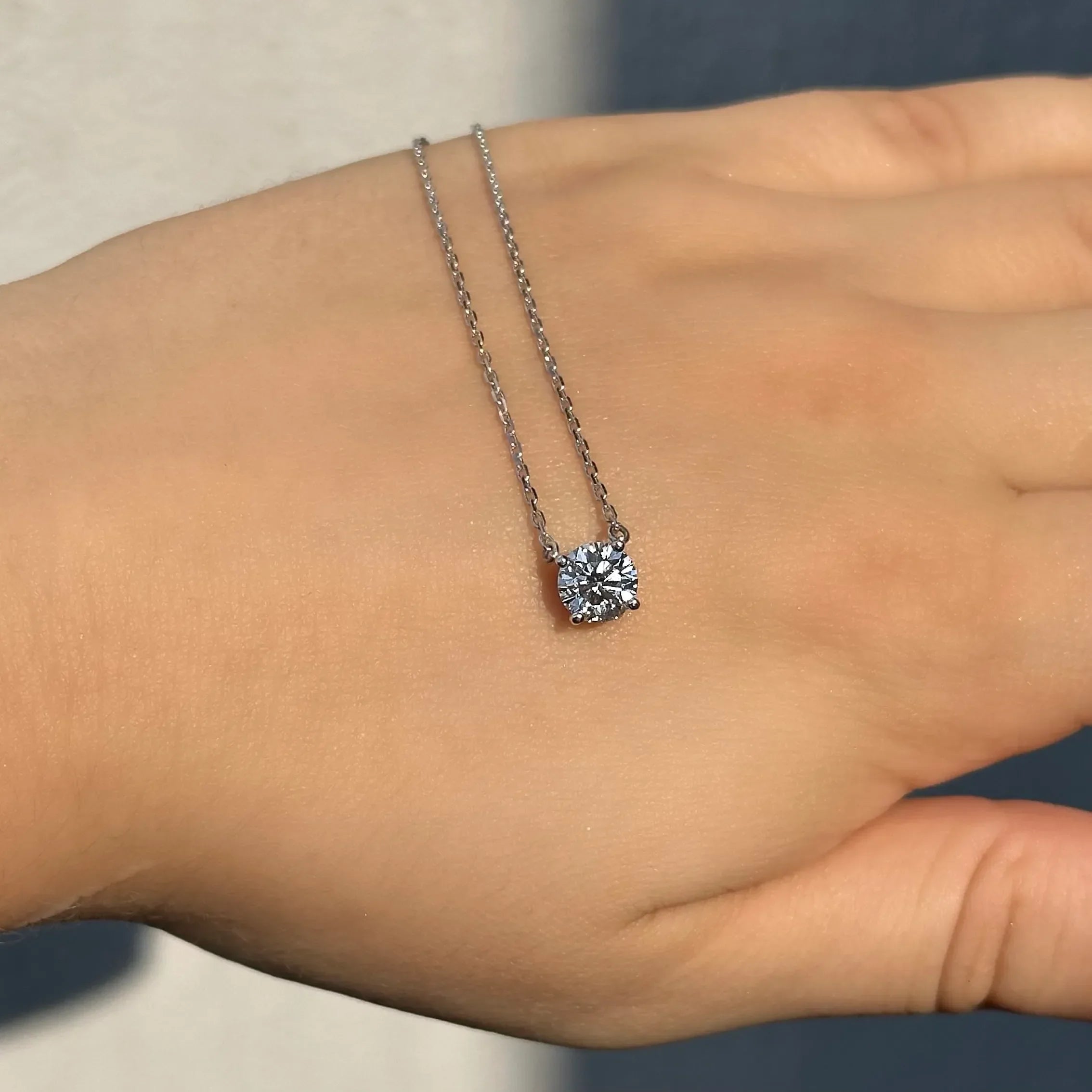 Lab-grown diamond solitaire pendant necklace on a hand in natural light