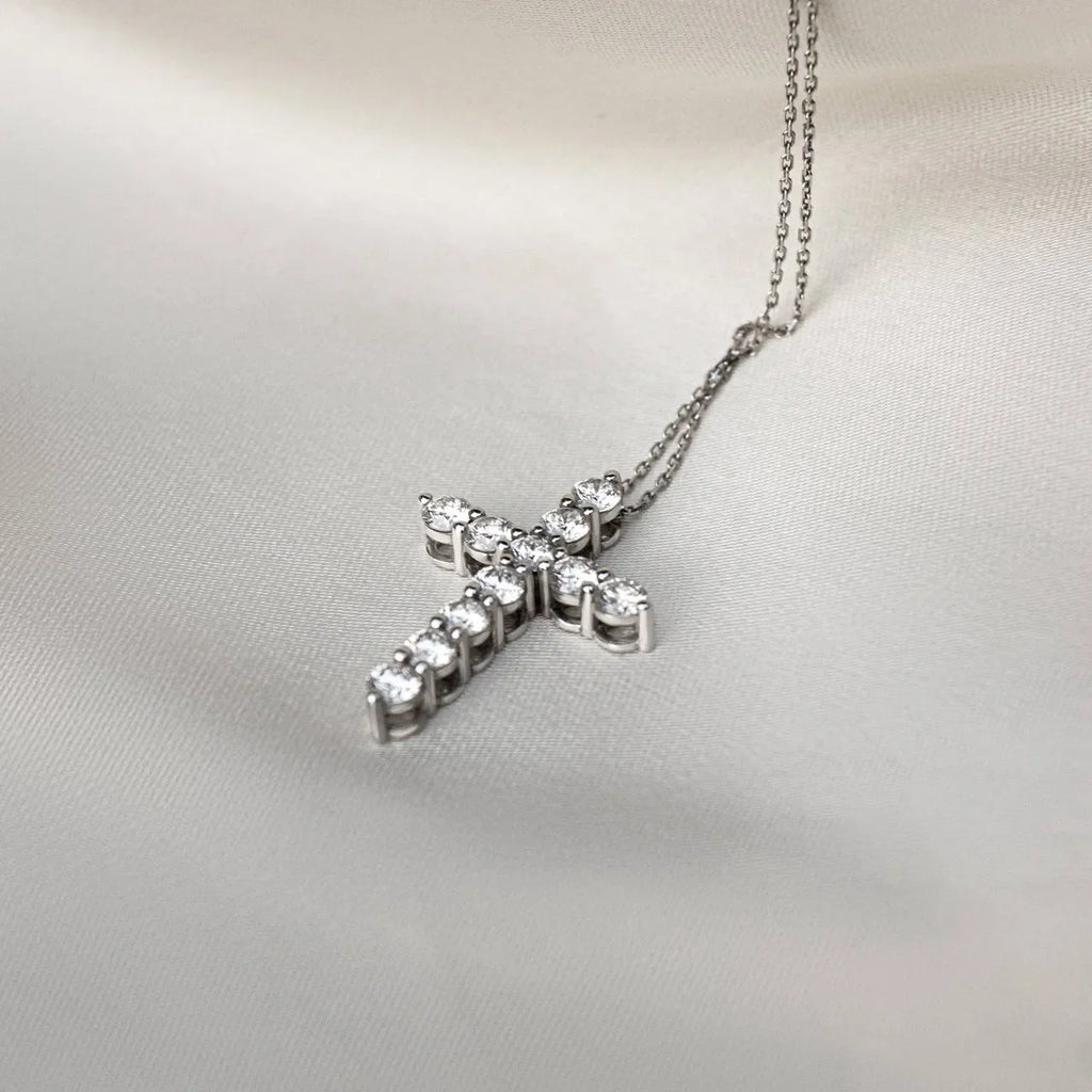 Lab-grown diamond cross pendant necklace on a silver chain resting on ivory fabric