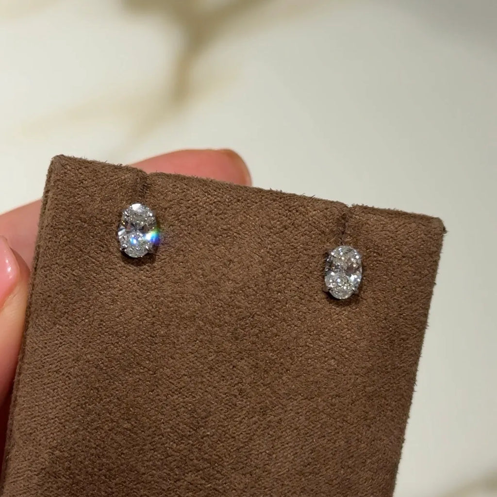 Oval lab-grown diamond stud earrings displayed on brown suede holder