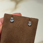 Oval lab-grown diamond stud earrings displayed on brown suede holder