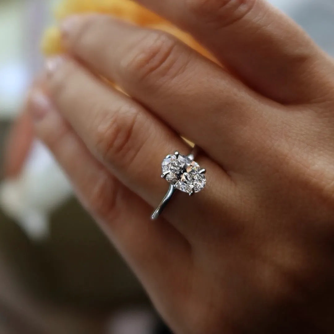 Close-up of a hand wearing a two-stone lab-grown diamond ring on a silver band.