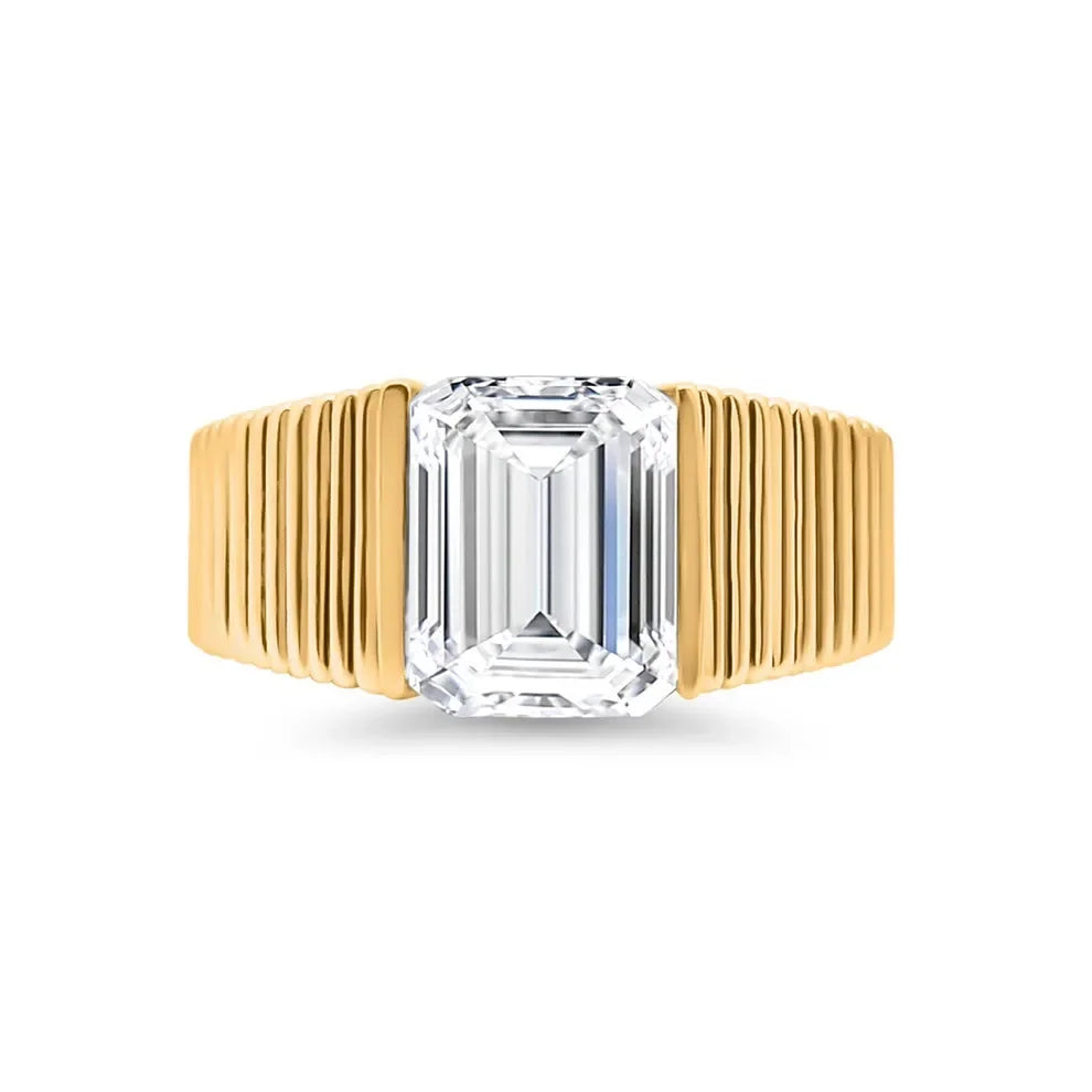 Emerald cut lab-grown diamond ring with grooved yellow gold band on white background