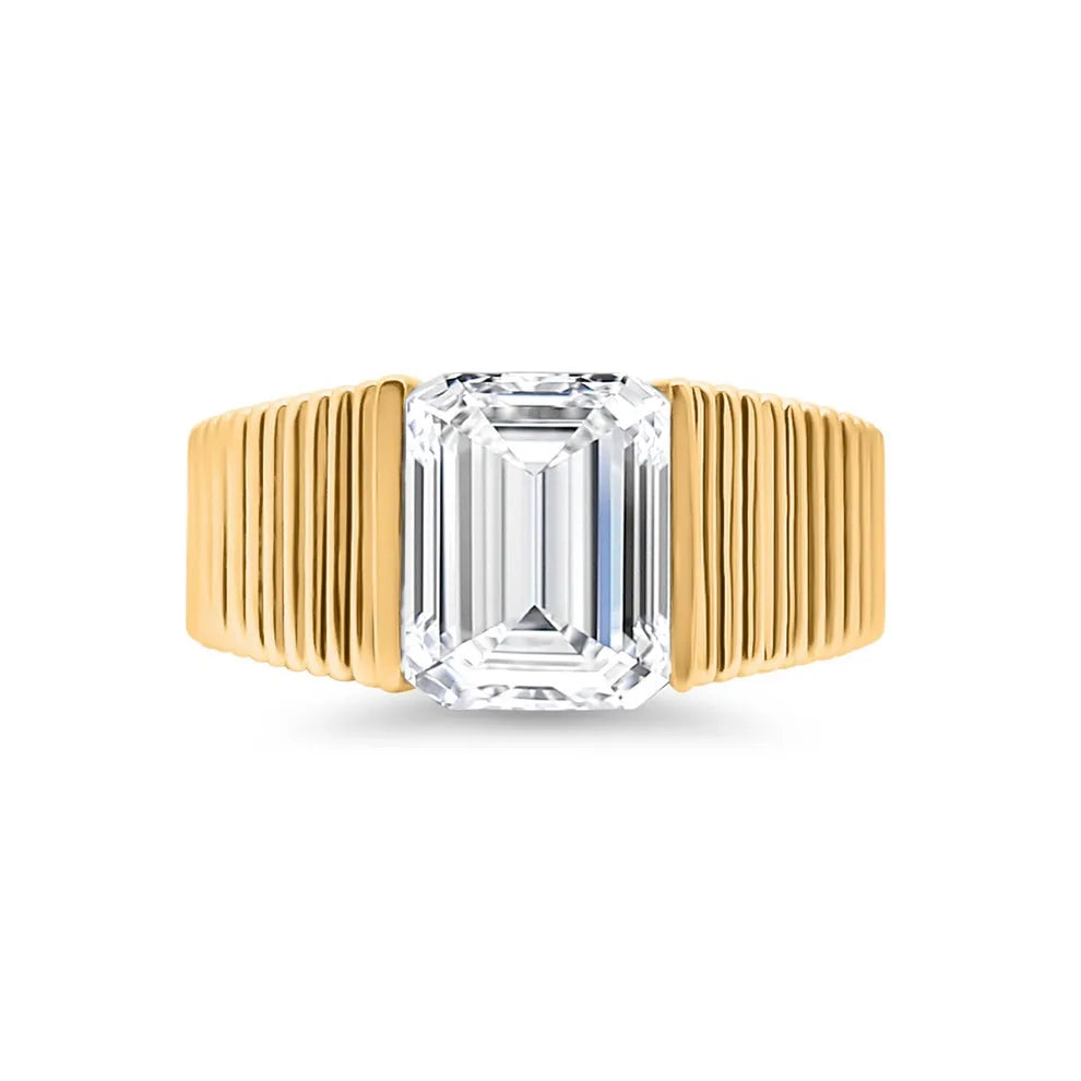 Emerald cut lab-grown diamond ring with grooved yellow gold band on white background