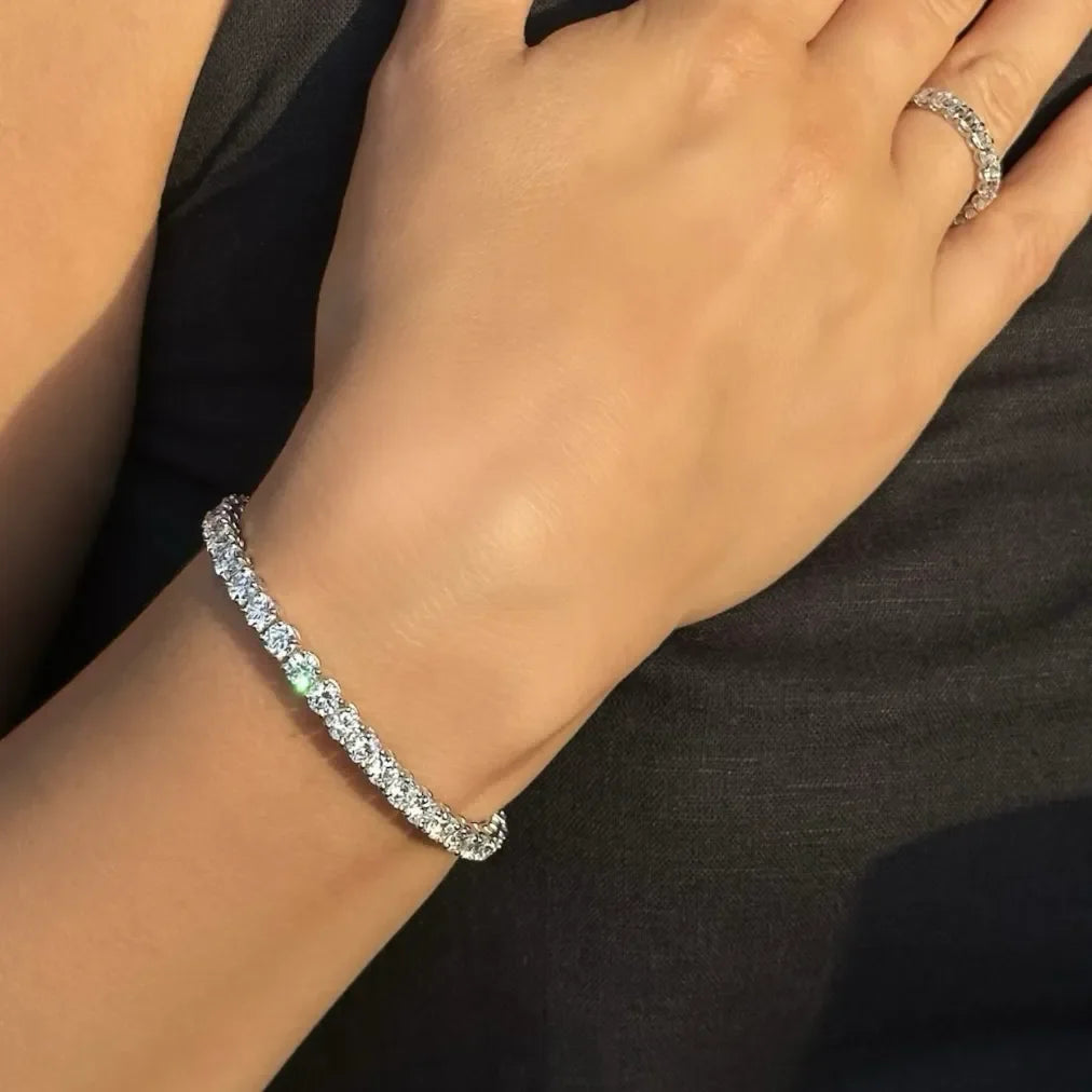 Hand wearing lab-grown diamond tennis bracelet and eternity ring in sunlight