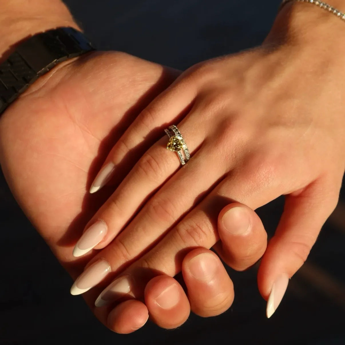 Hand wearing a yellow lab-grown diamond ring with pavé band, held by another hand