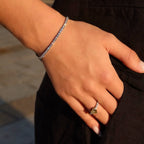 Hand wearing a lab-grown diamond tennis bracelet and a yellow diamond ring