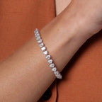 Lab-grown diamond tennis bracelet on wrist, elegant jewelry in close-up, orange blazer